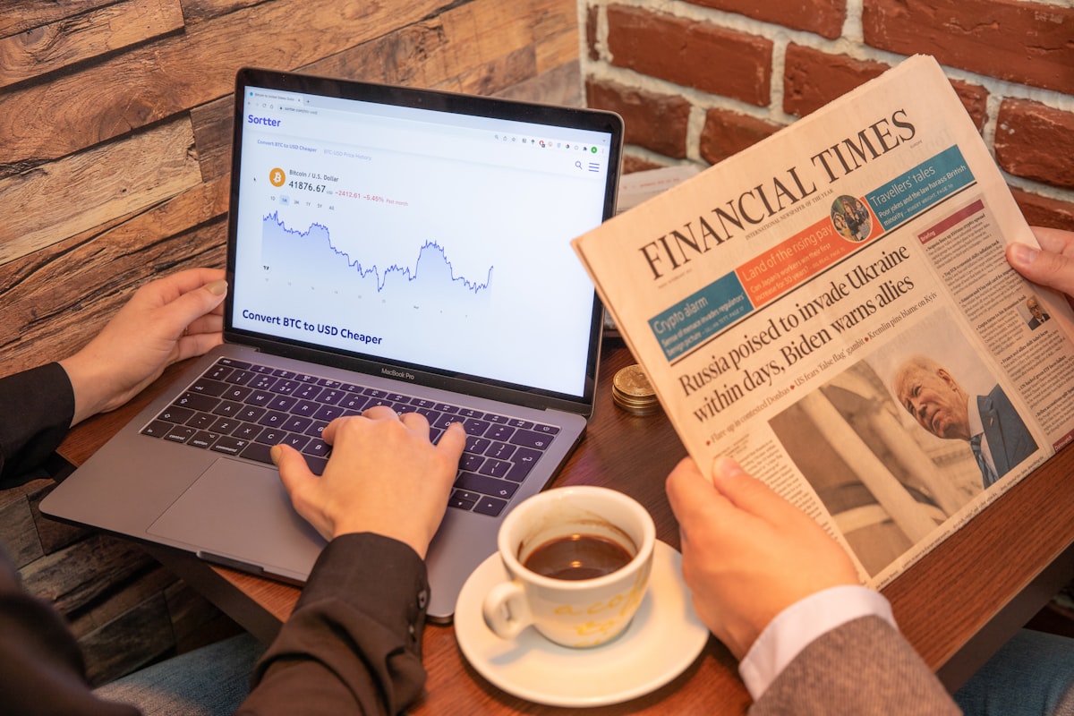 Drinking coffee in a coffee shop checking Bitcoin chart with Financial Times, from France, aside.